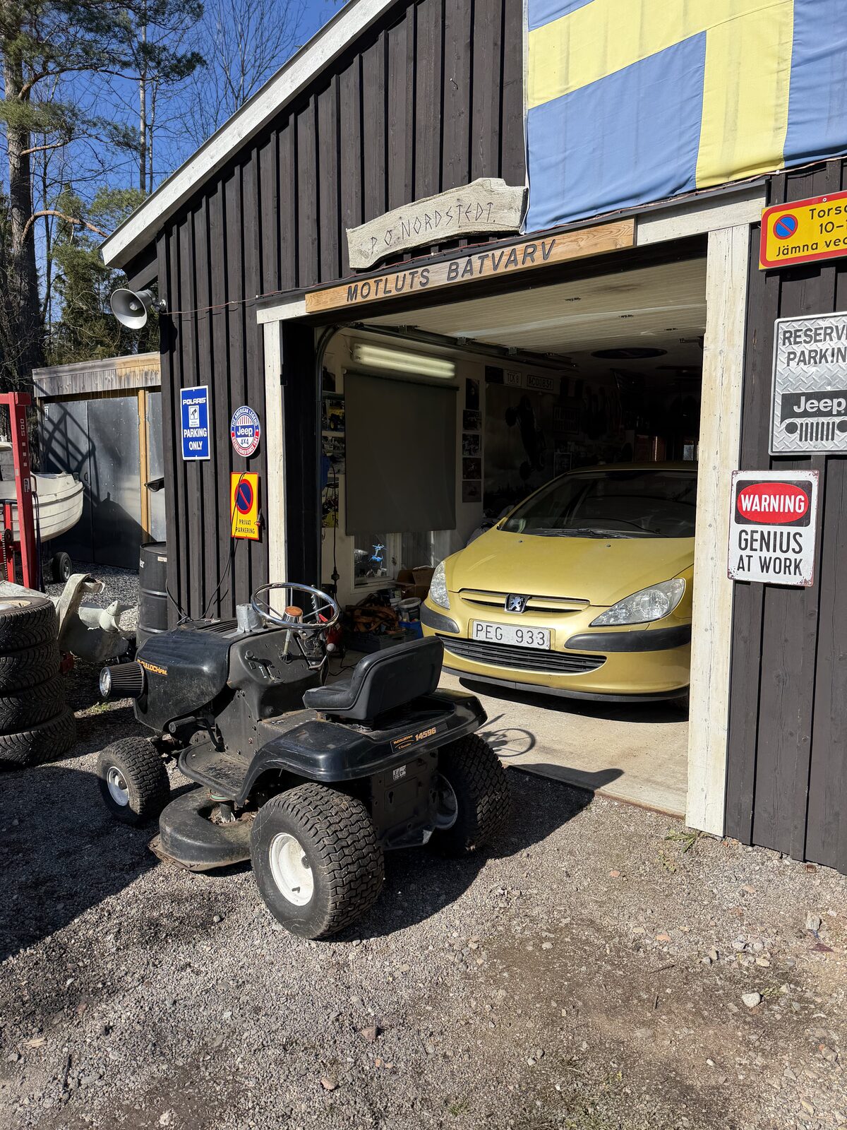 Gul Peugeot inne i garaget med åkgräsklippare framför