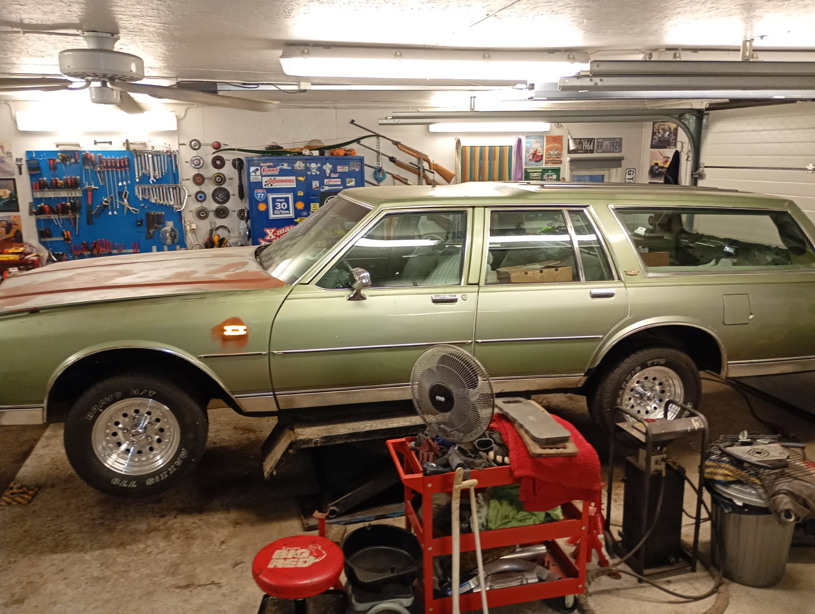 Grön Chevy Caprice stationsvagn uppe på lyften inne i garaget