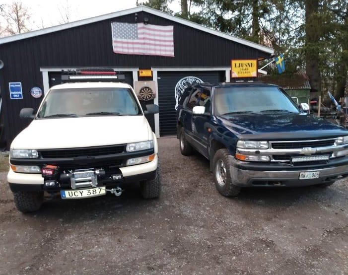 Två Chevy-pickuper framför garaget med amerikansk och svensk flagga