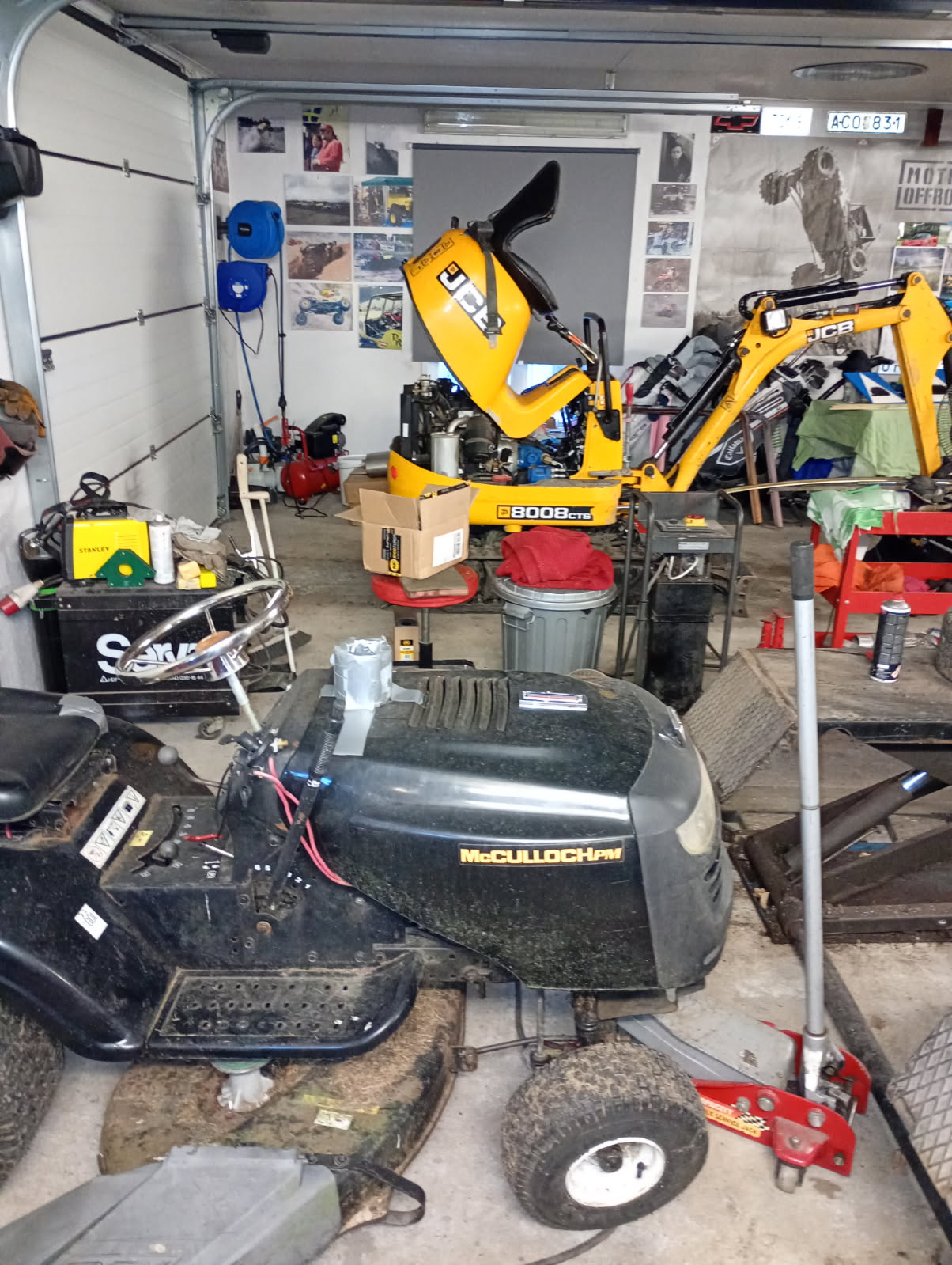 JCB minigrävare och McCulloch åkgräsklippare inne i garaget
